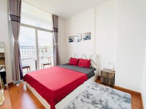 1 dormitorio con cama roja y ventana grande en ALPHA HOMESTAY MARINA 2 Phòng Ngủ View Sông en Ấp Ðông An (1)
