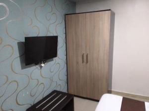 a bedroom with a cabinet and a tv on a wall at Light house hotel in Lekki