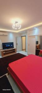 a bedroom with a red bed and a flat screen tv at برج حورس in Obour