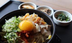 a bowl of food with an egg on a table at Jeonju Wangyijimil Hanok Hotel in Jeonju