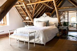 a bedroom with a white bed and a chair at Cape Dutch @ Keerweder in Franschhoek
