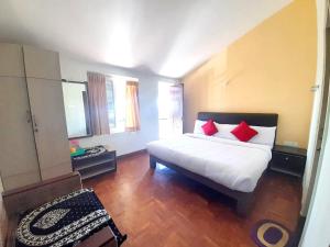 sypialnia z białym łóżkiem z czerwonymi poduszkami w obiekcie A2 Home Stay w mieście Kodaikānāl