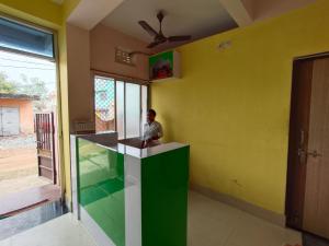 a man sitting at a counter in a room with yellow walls at Shivangi Eco in Puri