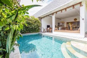 an outdoor swimming pool with a villa in the background at Adorable 1BR villas in the herat of Seminyak in Seminyak