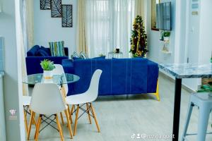 a living room with a blue couch and white chairs at Crystal Apartments Area 43 in Lilongwe