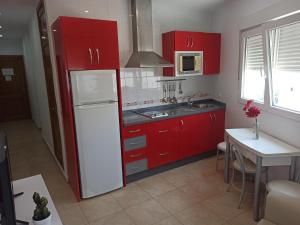 コニル・デ・ラ・フロンテーラにあるApartamento Sebastián Solo Familiasのキッチン(赤いキャビネット、白い冷蔵庫付)