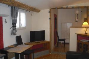 ein Wohnzimmer mit einem TV und einem Tisch mit einem sidx sidx in der Unterkunft Le Rosier in Gordes