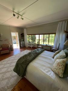 a large white bed in a bedroom with windows at Tafeni Farm Cottages in Swartberg