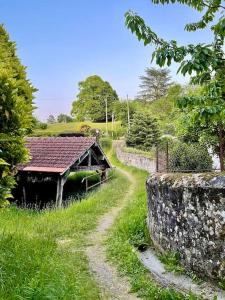 a path leading to a building with a stone wall at Les Maisons d'Auré: Le studio in Putanges +3 photos