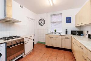 a kitchen with a stove and a clock on the wall at Four Bedroom City Centre Large Derby House Contractors Leisure in Derby