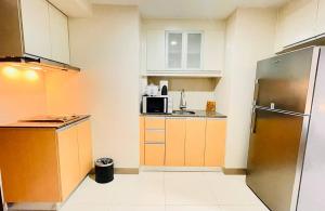 a small kitchen with a refrigerator and a microwave at Thompson Suites - 2 beds, One Uptown Residences 28F A - XBOX & Netflix in Manila