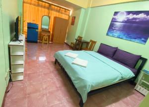 um quarto com uma cama com almofadas roxas e uma televisão em DD Mansion em Ban Talat Rangsit