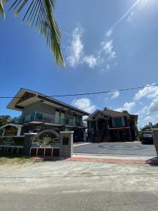 a house with a palm tree in front of a street at Airport Kota Bharu Homestay & Riverview Inn in Kota Bharu