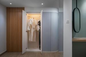 a dressing room with a closet with a white robe at The Bayou Hotel Langkawi in Pantai Cenang