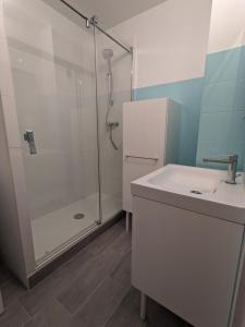 a white bathroom with a shower and a sink at Coquet appartement a 300 m du port du Pouliguen in Le Pouliguen