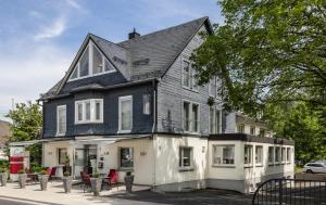 a black and white house with red chairs on the street at EWERTS Hotel in Netphen