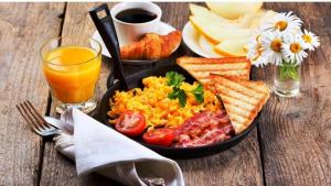 a plate of breakfast food with eggs toast and a glass of orange juice at Hotel M in Vijayawāda