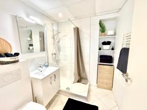 ein weißes Bad mit einer Dusche und einem Waschbecken in der Unterkunft Studio center 104 in Cannes
