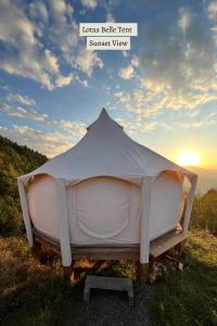 a tent sitting in the grass with the sunset in the background at Glamping Tago in Khulo