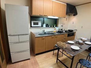 a kitchen with a table and a white refrigerator at -0 meter to station- Tokyo, Asakusa, Ueno, Skytree tower and Akihabara entire house for 14 guests -駅まで0メートル- 東京 浅草 上野 スカイツリー 秋葉原一棟貸切14名様 in Tokyo