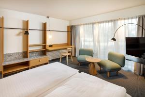 um quarto de hotel com uma cama e duas cadeiras e uma secretária em Alpha-Palmiers by Fassbind em Lausanne