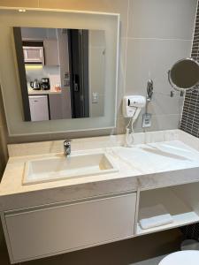 a bathroom with a white sink and a mirror at Studio Helbor Stay Batel - Aconchegante com Vista e Localização Privilegiada in Curitiba