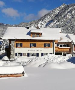 ein schneebedecktes Gebäude vor einem Berg in der Unterkunft Das Edelweiss in Grän