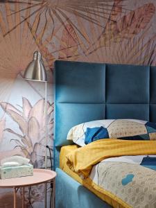 Turquoise Apartment (Private Garage) في نوفي ساد: سرير مع اللوح الأمامي الأزرق بجانب طاولة