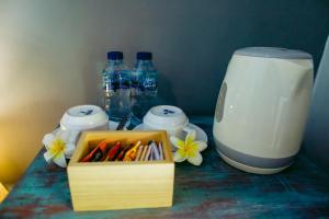 un tavolo con una scatola di penne e bottiglie d'acqua di Kinton Guesthouse a Nusa Penida