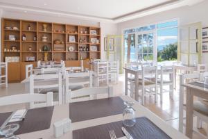 een restaurant met witte tafels en stoelen en een groot raam bij Mare Hotel Apartments in Agios Nikolaos