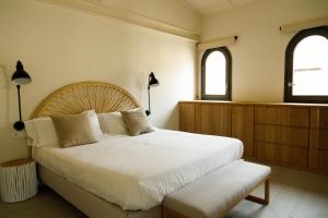 a bedroom with a large white bed and two windows at La Comuna by Bon Dia Residences in Girona