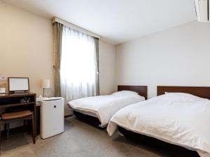 a bedroom with two beds and a desk and a window at Seoul Garden Hotel in Hakodate