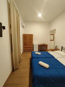 a bedroom with two beds with blue sheets and a table at Hotel Faraglione in Vulcano