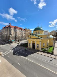 a yellow building with a green roof on a city street at Laima V. Apartments in Riga