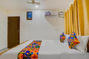 a bedroom with a white bed with a colorful blanket at FabExpress Rithun Residency in Bangalore