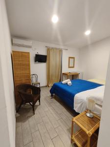 a bedroom with a bed and a chair and a tv at Hotel Faraglione in Vulcano