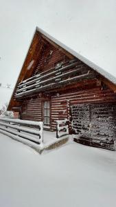 une cabane en rondins avec de la neige sur le toit dans l'établissement Cozy House Blidinje, à Blidinje