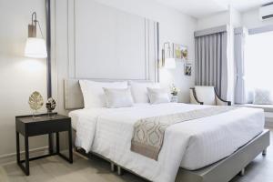 a white bedroom with a large bed and a table at THE NAVY HOUSE HOTEL in Sattahip