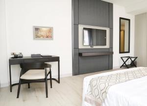 een slaapkamer met een bureau, een bed en een televisie bij THE NAVY HOUSE HOTEL in Sattahip