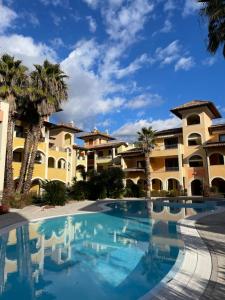 una piscina frente a un edificio con palmeras en Benaco Village Home, en Toscolano Maderno
