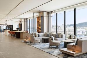 a living room with couches and tables and windows at Nagasaki Marriott Hotel in Nagasaki