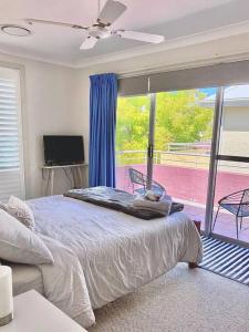 a bedroom with a bed and a large window at Bec's Beach House Getaway in Batemans Bay
