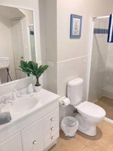 Baño blanco con aseo y lavamanos en Bec's Beach House Getaway, en Batemans Bay