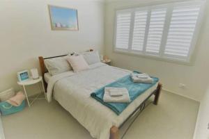 1 dormitorio con 1 cama con toallas en Bec's Beach House Getaway, en Batemans Bay