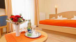 ein Hotelzimmer mit einem Bett und einem Tisch mit einer Blumenvase in der Unterkunft Hotel garni Arte Vita in Heringsdorf