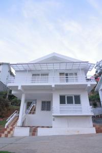 a white house with a balcony at Seven Endue Delight with Mountain view on the Hill Top in Ooty
