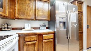 a kitchen with wooden cabinets and a stainless steel refrigerator at Aspen Creek #311 condo in Mammoth Lakes +26 photos