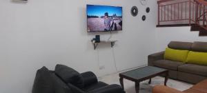 un soggiorno con un divano e una TV a parete di LOTUS HOMESTAY a Seri Kembangan