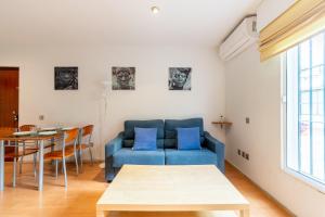 sala de estar con sofá azul y mesa en Holi-Rent Esperanza, en Sevilla