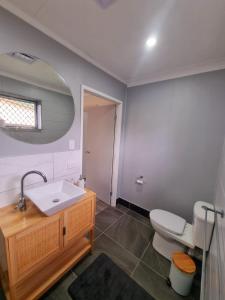 a bathroom with a sink and a toilet and a mirror at Cosy & Convenient: pools, shops, uni, hospital in Ross River